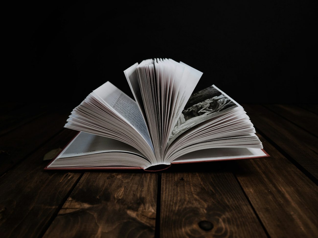 An open bilingual poetry edition on a dark wooden table showing the original Spanish text on the left page and the English translation on the right, with annotations in pencil and a small lamp casting warm light.