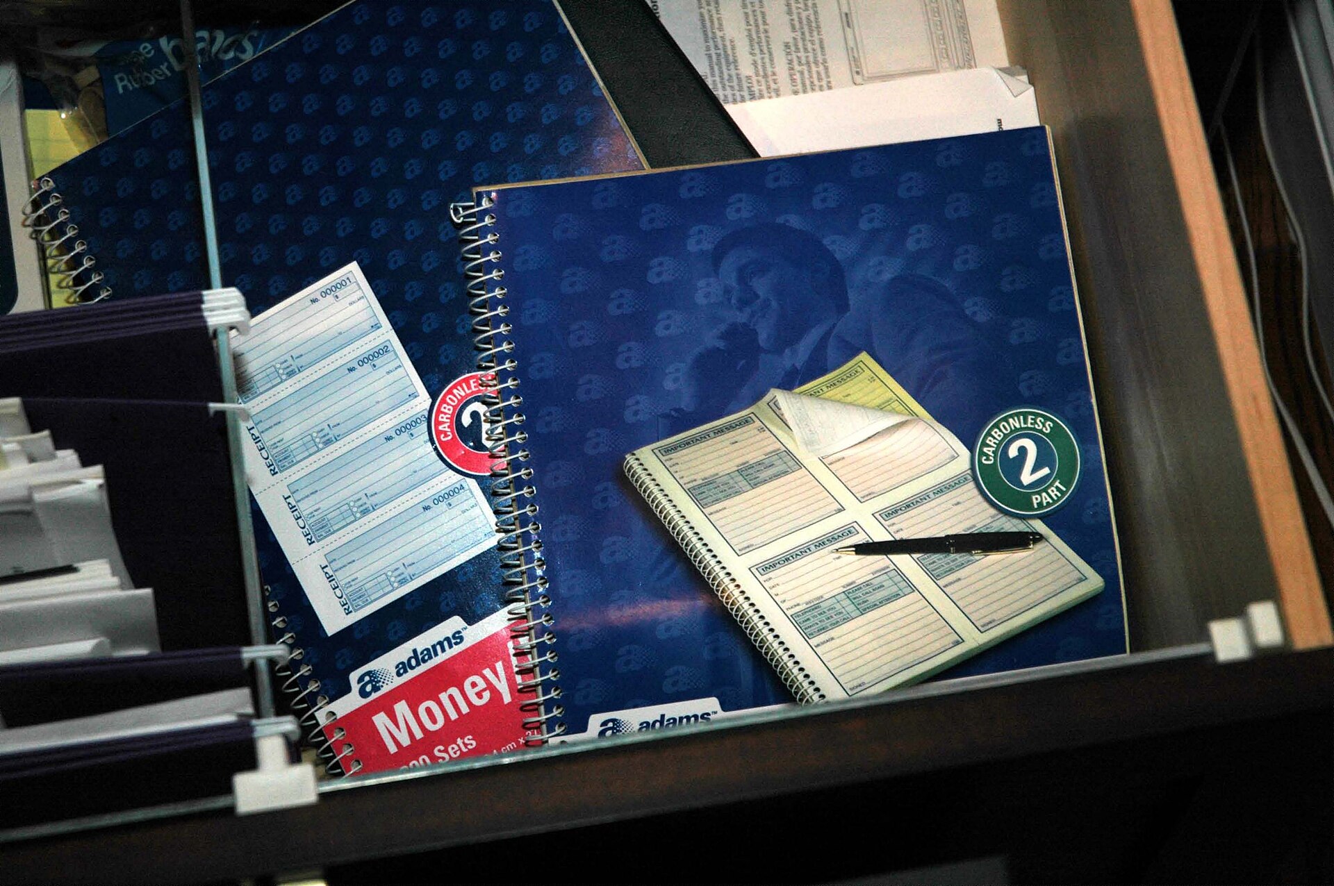Carnet ouvert et stylo posés sur un bureau en bois, lampe allumée au fond