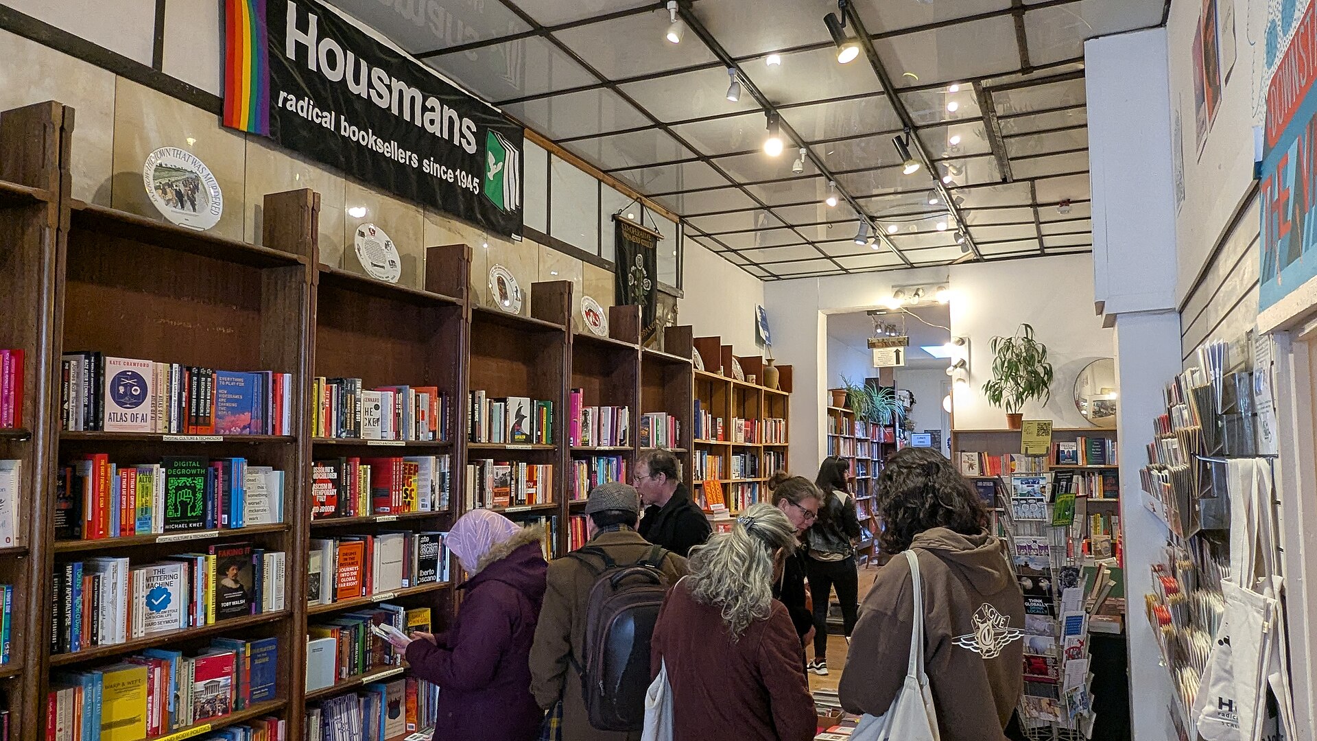 Intérieur d'une librairie indépendante, rayonnages de bois et tables de nouveautés au premier plan