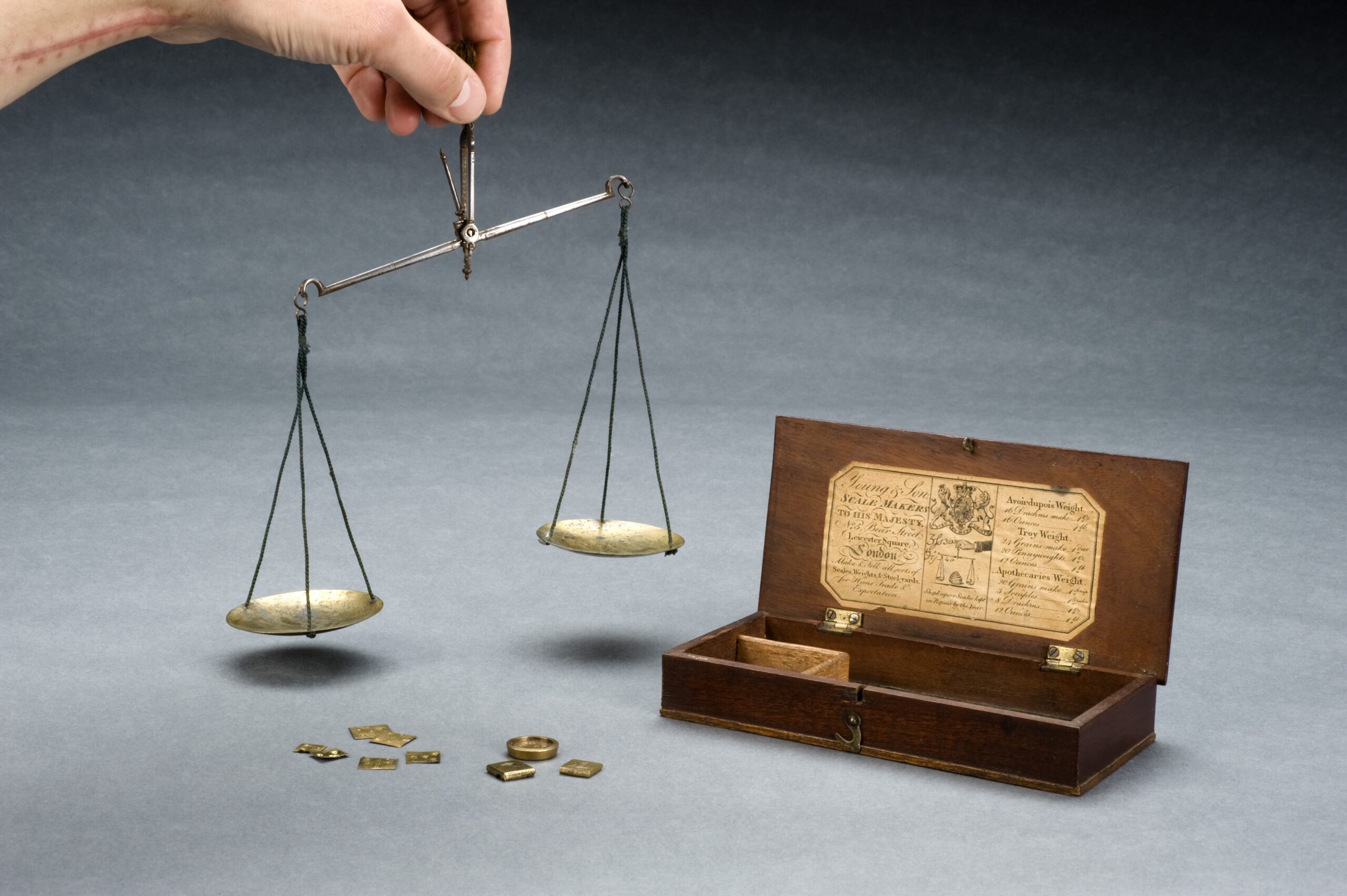 Balance à deux plateaux en laiton posée sur une table, plateaux presque à l'équilibre