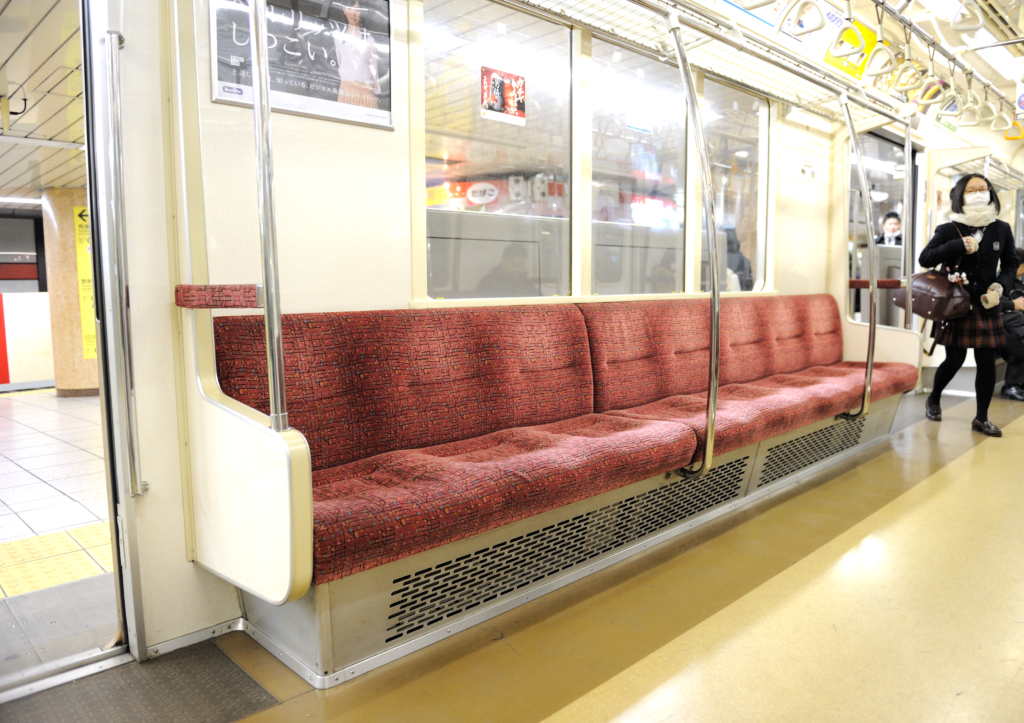 Intérieur d'une rame de métro en marche, barres verticales et voyageurs debout serrés