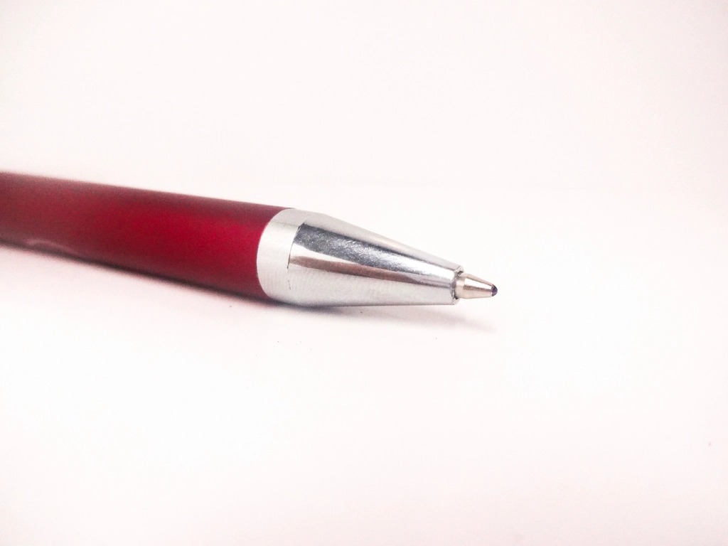 Stylo rouge posé sur une page imprimée couverte de corrections manuscrites dans la marge