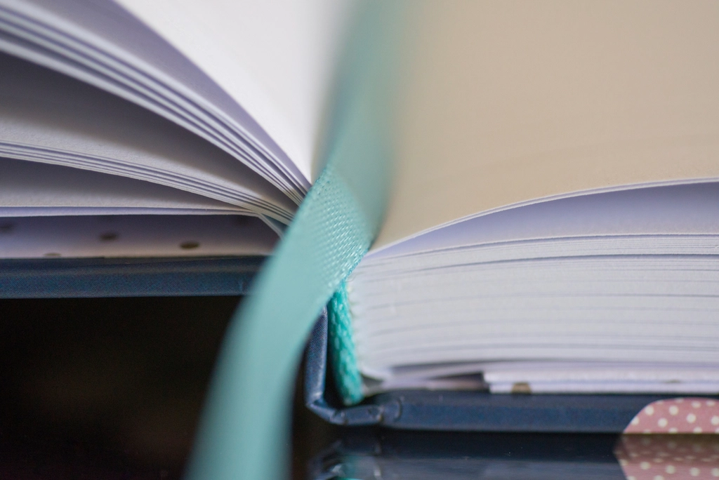 Livre ouvert avec un signet de papier glissé entre deux pages, coin de table visible