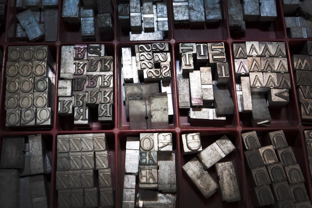 Caractères métalliques d'imprimerie rangés dans un casier, lettres et signes visibles de près