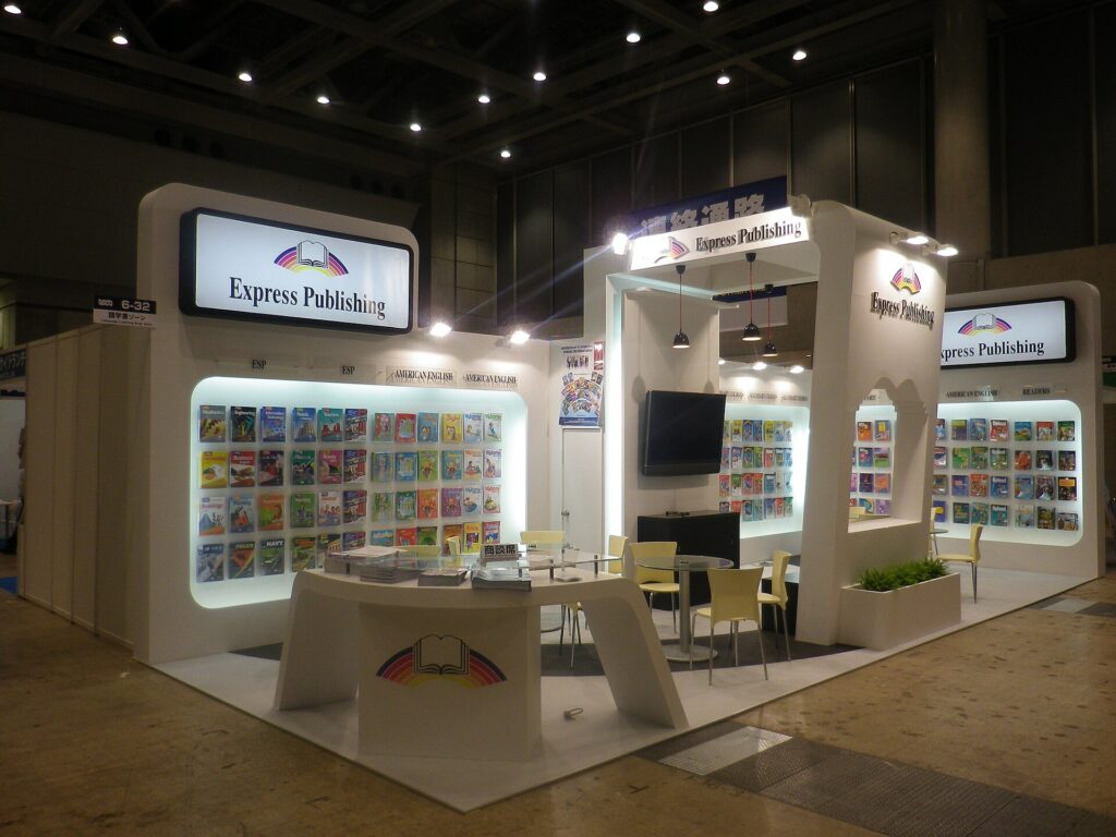 Stand d'un salon professionnel du livre, tables basses et rayonnages d'échantillons