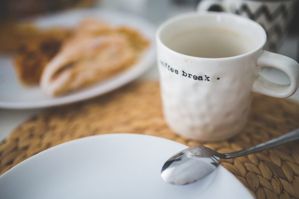 Mug blanc &eacute;br&eacute;ch&eacute; pos&eacute; au bord d'un &eacute;vier avec une cuill&egrave;re &agrave; l'int&eacute;rieur