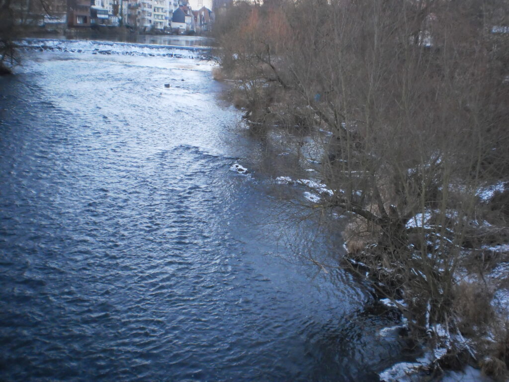 Pont de pierre au-dessus d'une rivi&egrave;re gel&eacute;e, glace craquel&eacute;e et berges enneig&eacute;es