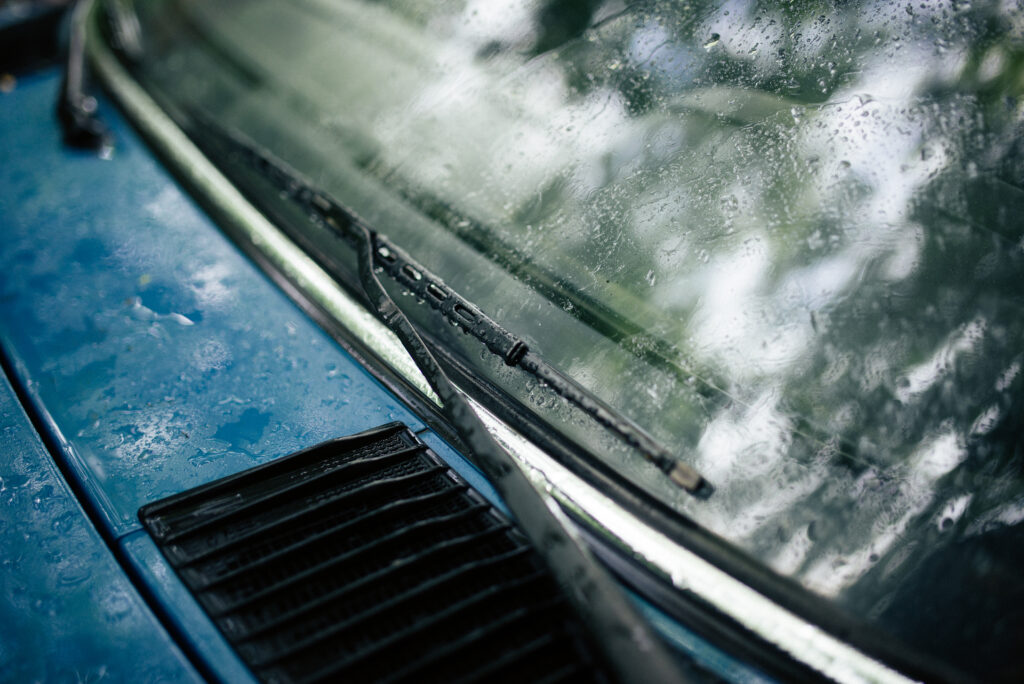 Vue depuis l'int&eacute;rieur d'une voiture sur une maison et une haie, pare-brise mouill&eacute;