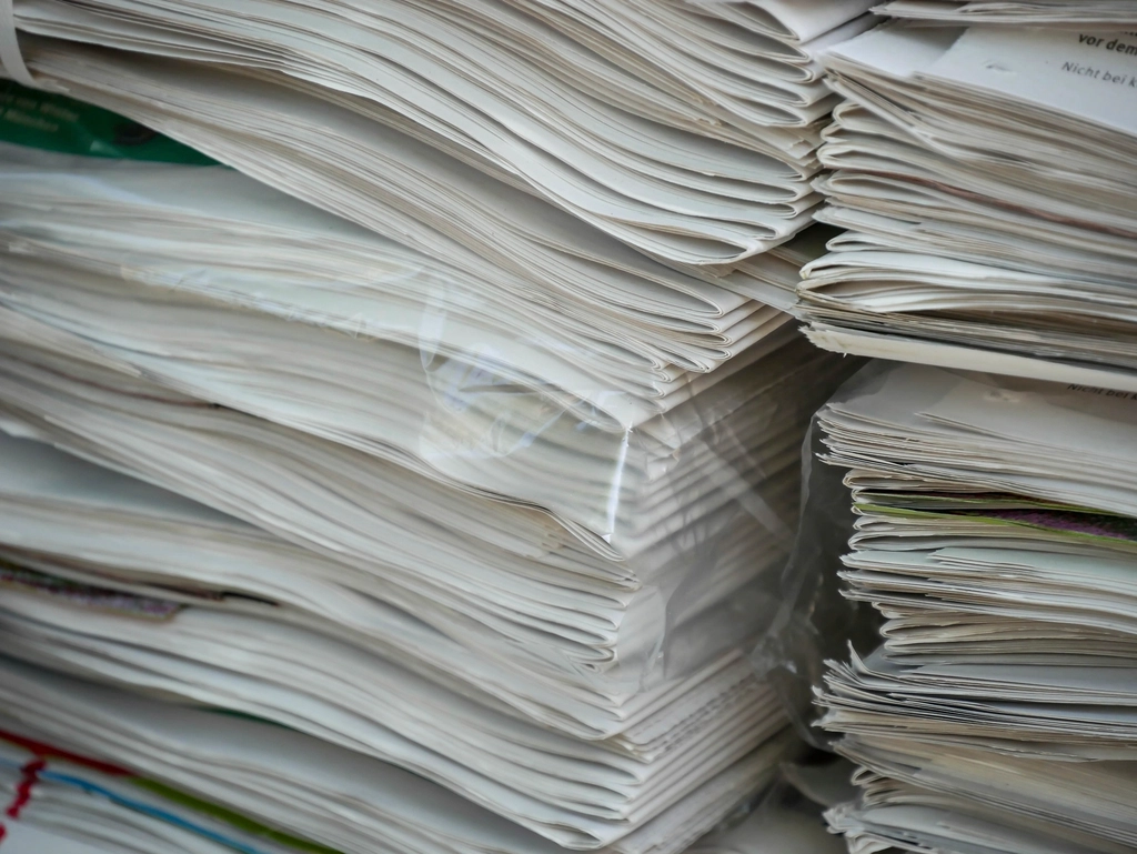 Pile de manuscrits imprimés reliés par des élastiques sur un bureau encombré